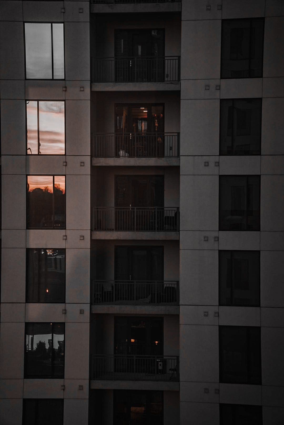 Apartment balconies at dusk with the last orange light reflected in upper windows.